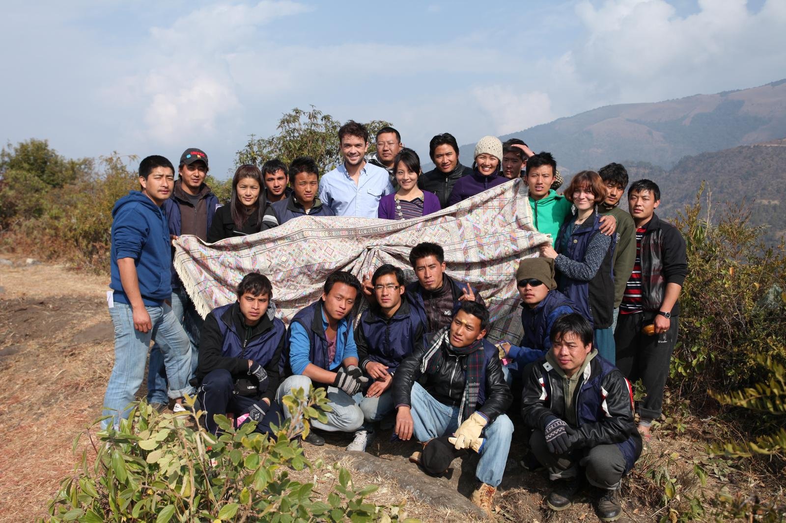 Karma Deki and the Kushuthara film crew holding a traditional Bhutanese textile in the mountains