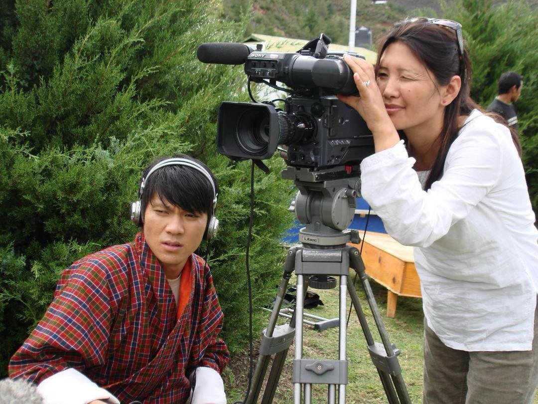 Karma Deki directing behind a professional film camera on set in Bhutan