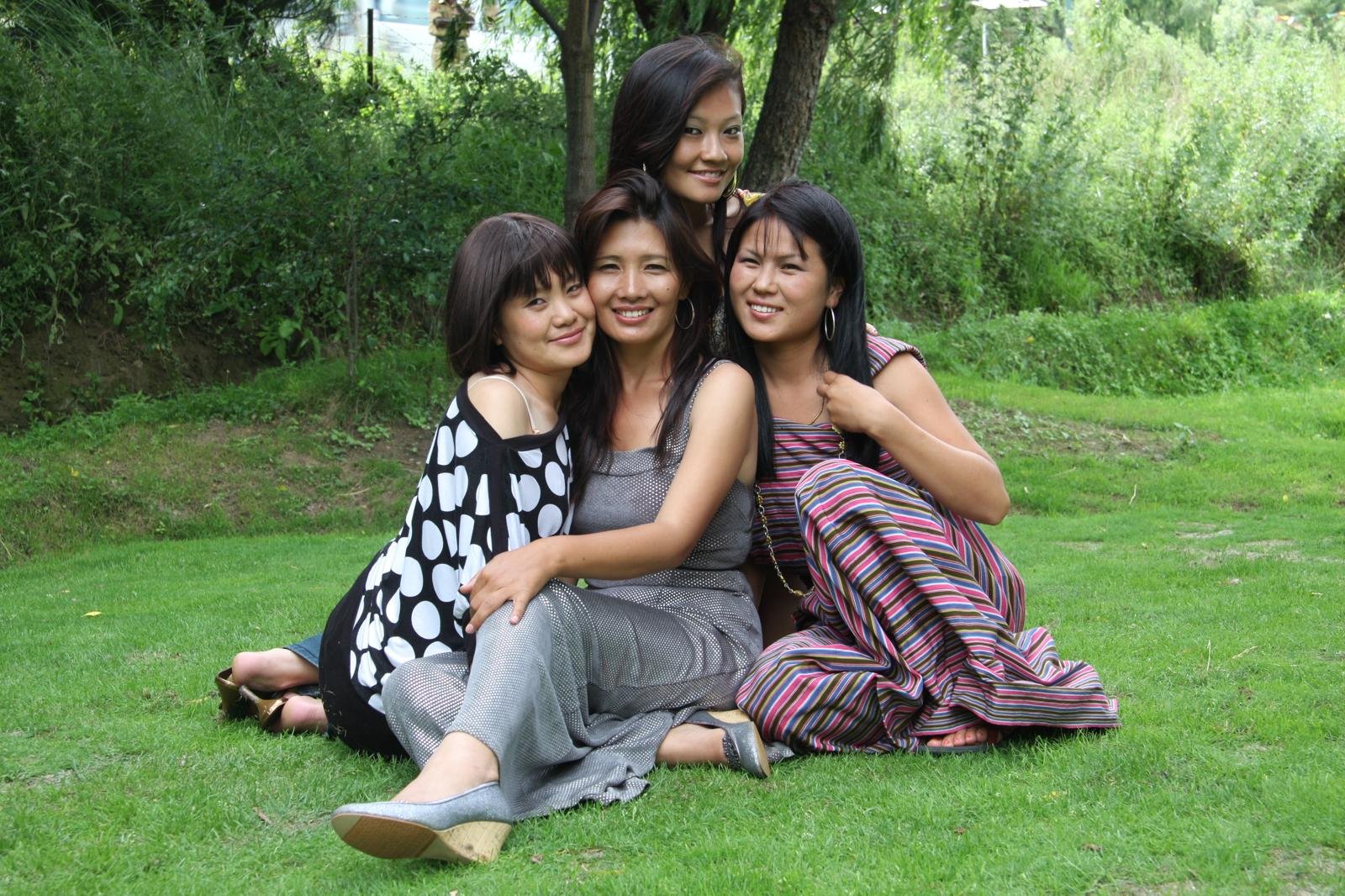 Karma Deki with close friends sitting together on grass in Bhutan