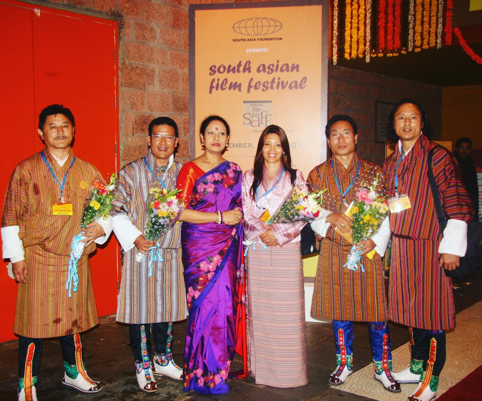 Karma Deki and Bhutanese delegation at the South Asian Film Festival holding flower bouquets